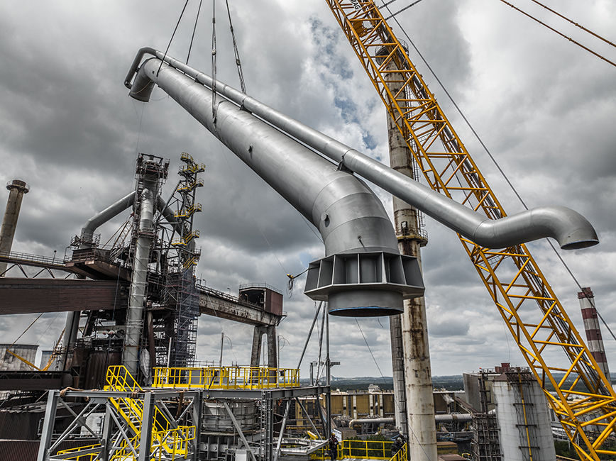Bau der Gasreinigungsanlage von Primetals Technologies - ein 1000-Tonnen-Kran hebt das letzte Stück der herabgehenden Leitung in Position. 